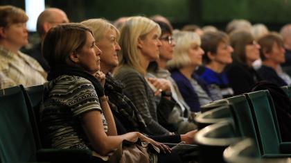 people sat in theatre seats looking off camera