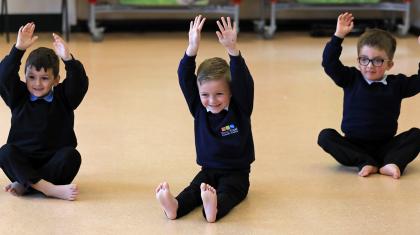 Three boys sat on the floor with hands above their heads