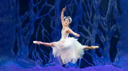 Ayami Miyata in a sparkline whide snowflake dress leaps in a grand jeté