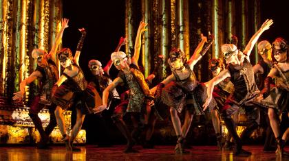 A groups of dancers on stage in masks and 18th century attire