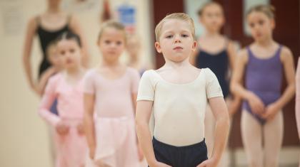 A boy stood with arms held in ballet position