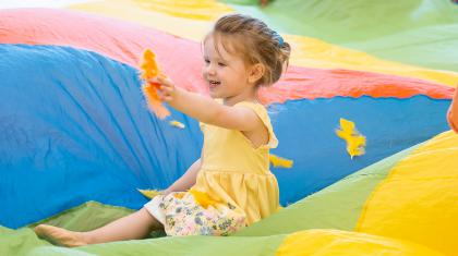 Little girl in a rainbow parachute playing with a feather