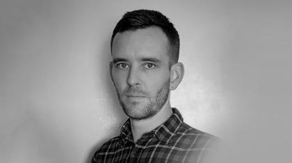 Black and white headshot of a man in a checkered shirt