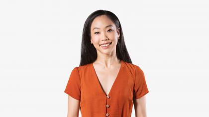 A headshot of a female dancer with dark hair and orange dress