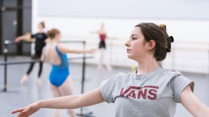 A young woman leaning backwards on a ballet barre