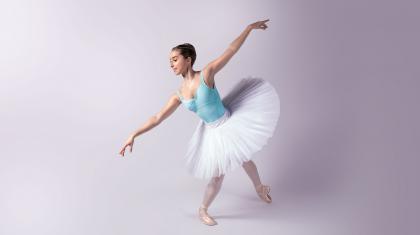 Female dancer in a blue leotard and white tutu on pointe