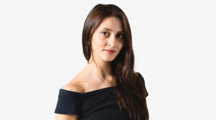 A headshot of a woman looking forward with dark brown hair and a black top