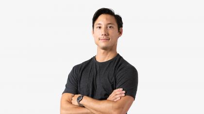 A headshot of a man stood with arms crossed in a dark grey t-shirt