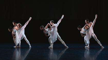 Three couples, each wearing white, a male holds steady a female who is leaning forward on one foot while the other leg is extended in the air behind her