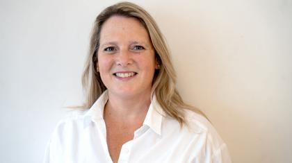 Woman with blonde hair wearing a white shirt smiles directly at the camera