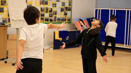A student stretches out their hand to mimic shooting energy. Another child pretends to be hit by its force.