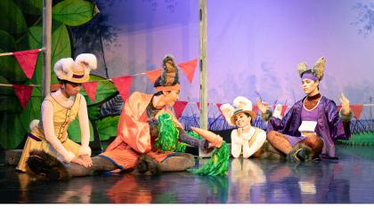 Dancers dressed as bunnies. One dancer checking another dancers leg, middle dancer holding two carrot stick pom poms, another dancer gazing in adoration and the last dancer meditating