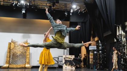 Man leaps (grand jete) across the stage dressed in green