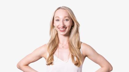 A headshot of a woman with blonde hair stood facing the camera in a white top.