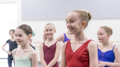 Class of young dance students with their hair tied in buns smiling