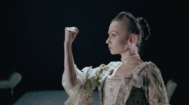 A female dancer looks at her clenched fist held aloft.