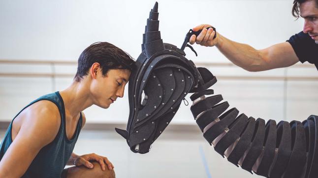 A dancer rests his forehead against a dragon puppet's forehead